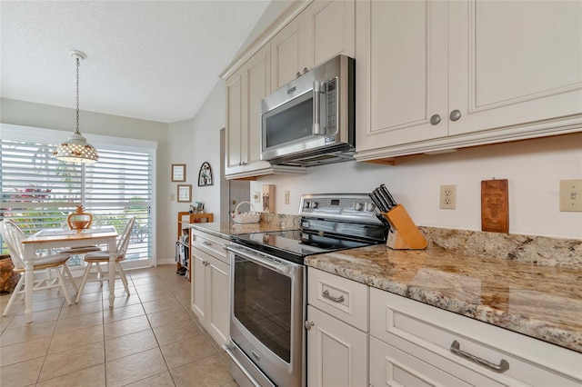 kitchen featuring light tile patterned flooring, a textured ceiling, appliances with stainless steel finishes, light stone countertops, and white cabinets