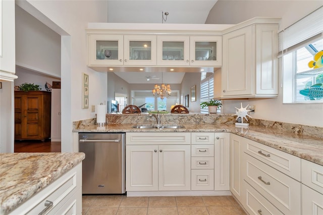 kitchen featuring sink, light tile patterned floors, white cabinetry, light stone counters, and stainless steel dishwasher