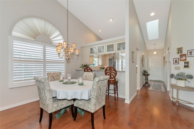 dining room featuring hardwood / wood-style floors, plenty of natural light, high vaulted ceiling, and a skylight