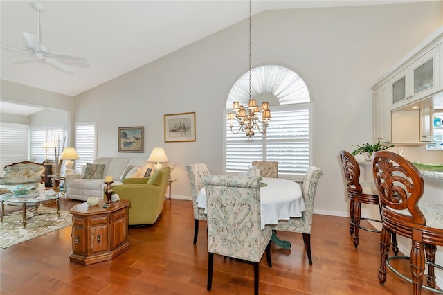 dining space with ceiling fan with notable chandelier, a wealth of natural light, high vaulted ceiling, and dark hardwood / wood-style floors