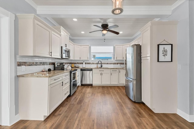 kitchen featuring sink, light stone counters, white cabinetry, appliances with stainless steel finishes, and backsplash