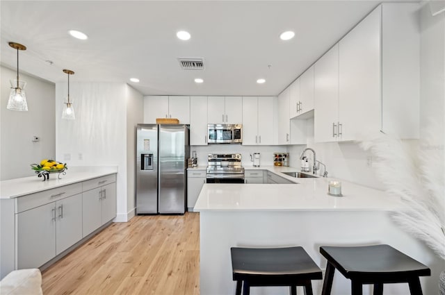 kitchen with pendant lighting, sink, appliances with stainless steel finishes, white cabinetry, and kitchen peninsula