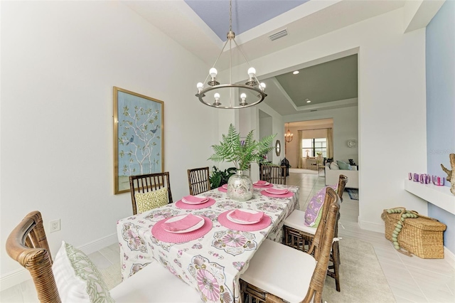 dining space with visible vents, baseboards, a tray ceiling, light tile patterned floors, and an inviting chandelier