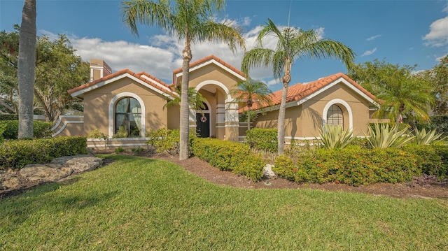 mediterranean / spanish home featuring a tile roof, a front lawn, and stucco siding