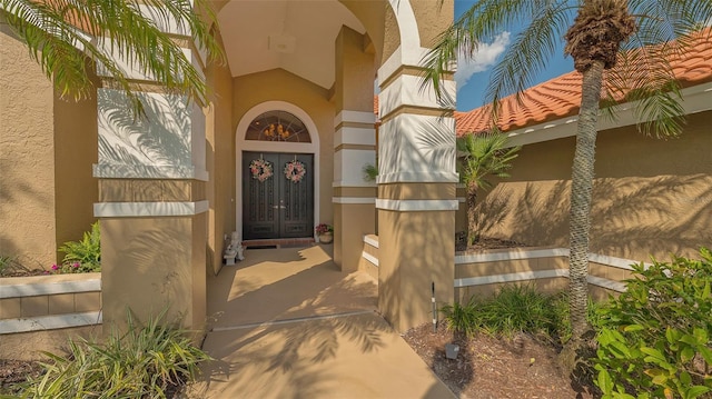 doorway to property featuring a tiled roof, french doors, and stucco siding