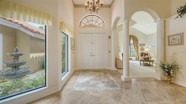 foyer featuring a healthy amount of sunlight, ornate columns, a towering ceiling, and arched walkways