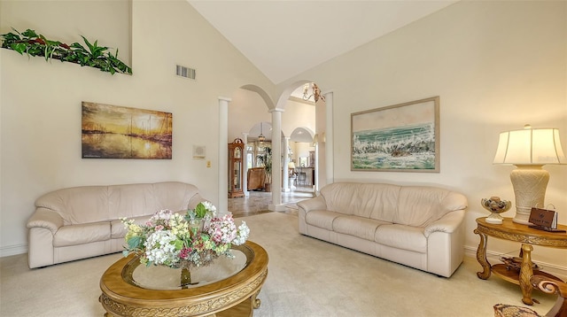 carpeted living area with baseboards, visible vents, arched walkways, ornate columns, and high vaulted ceiling