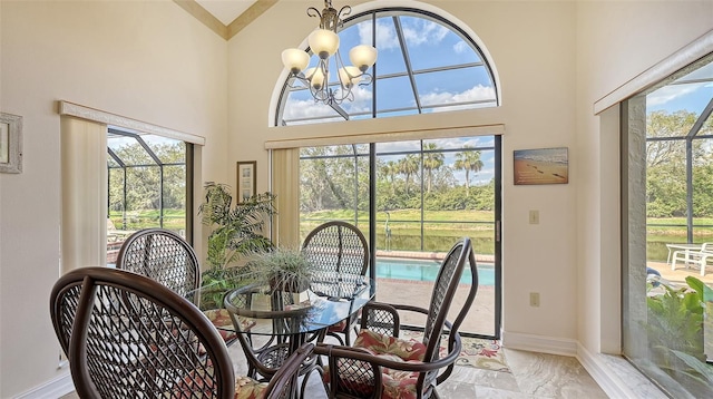 dining room with an inviting chandelier, a high ceiling, baseboards, and a wealth of natural light