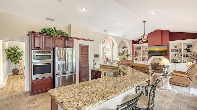 kitchen with arched walkways, stainless steel appliances, lofted ceiling, visible vents, and a sink