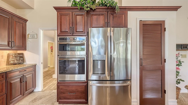 kitchen with appliances with stainless steel finishes, light stone counters, and decorative backsplash