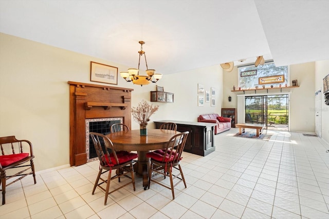 dining area with a tile fireplace, light tile patterned floors, and a chandelier