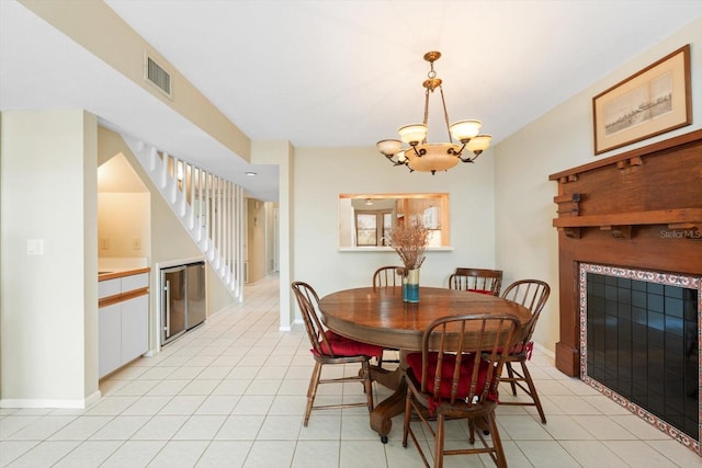 dining space with a notable chandelier, a tile fireplace, and light tile patterned floors