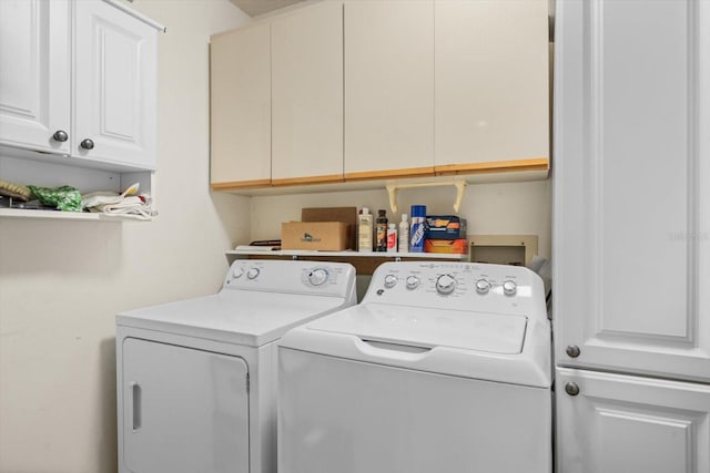 clothes washing area with cabinets and washer and dryer