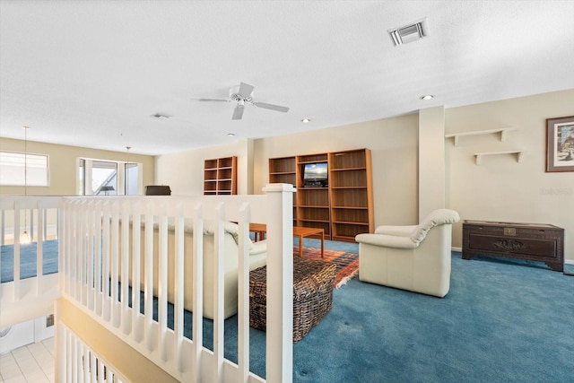 carpeted living room featuring ceiling fan and a textured ceiling