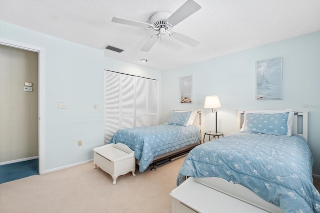 carpeted bedroom featuring ceiling fan, a closet, and a textured ceiling