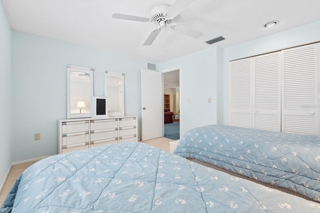 bedroom featuring light carpet, a textured ceiling, a closet, and ceiling fan