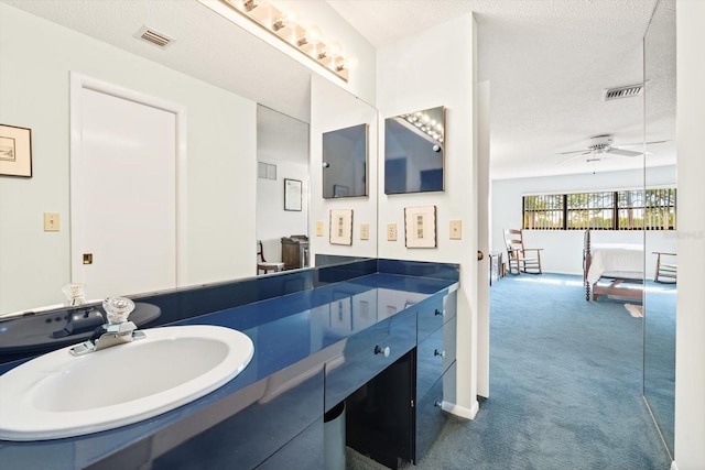 bathroom with ceiling fan, vanity, and a textured ceiling