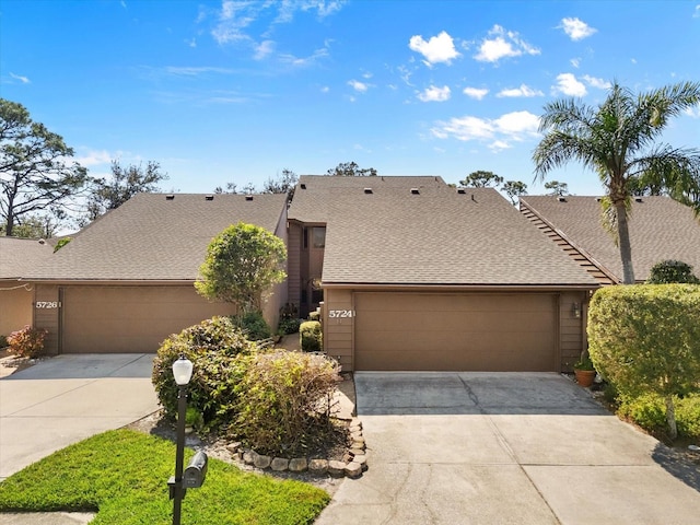 view of front of house with driveway, a garage, and roof with shingles