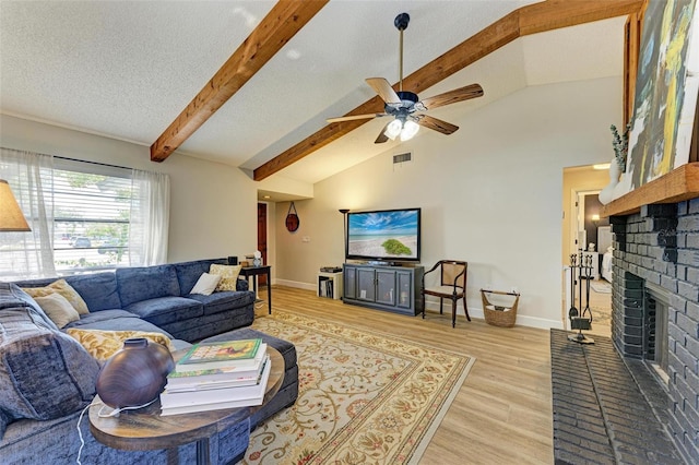 living room featuring a fireplace, lofted ceiling with beams, ceiling fan, a textured ceiling, and light hardwood / wood-style flooring