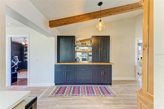 kitchen with light hardwood / wood-style flooring, wooden counters, hanging light fixtures, lofted ceiling with beams, and a textured ceiling