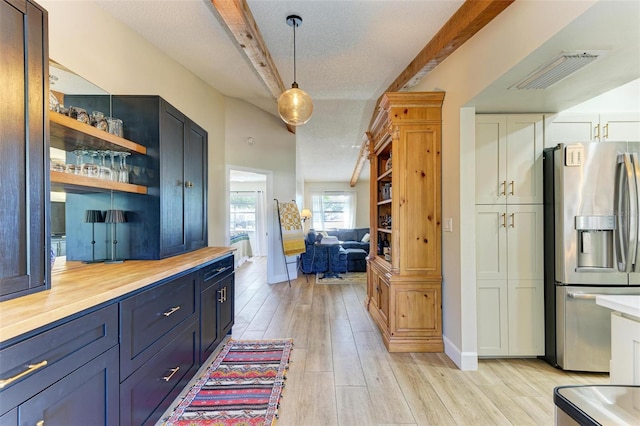 kitchen featuring stainless steel fridge with ice dispenser, decorative light fixtures, a textured ceiling, and white cabinets