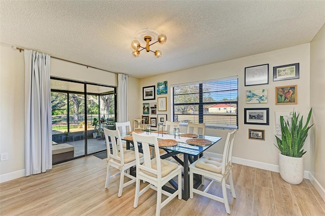 dining area with a notable chandelier, a textured ceiling, and light wood-type flooring