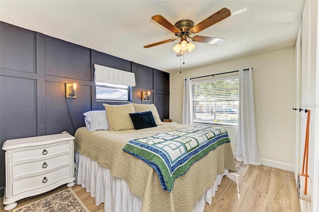 bedroom with a textured ceiling, light hardwood / wood-style flooring, and ceiling fan