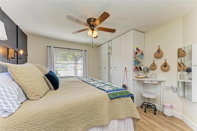 bedroom featuring a textured ceiling, light hardwood / wood-style flooring, a closet, and ceiling fan