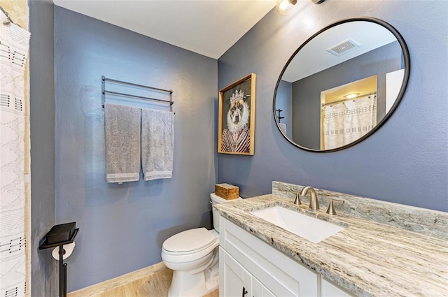 bathroom with vanity, toilet, and hardwood / wood-style floors