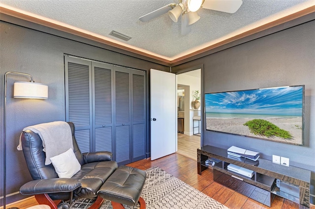 interior space featuring hardwood / wood-style flooring, ceiling fan, and a textured ceiling