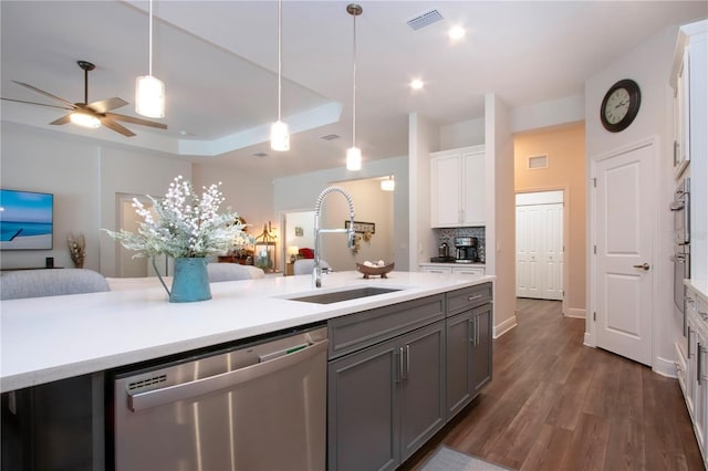 kitchen with pendant lighting, sink, white cabinets, dark hardwood / wood-style flooring, and stainless steel dishwasher