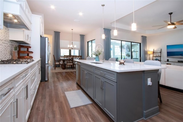 kitchen featuring pendant lighting, white cabinetry, stainless steel appliances, a center island with sink, and custom exhaust hood