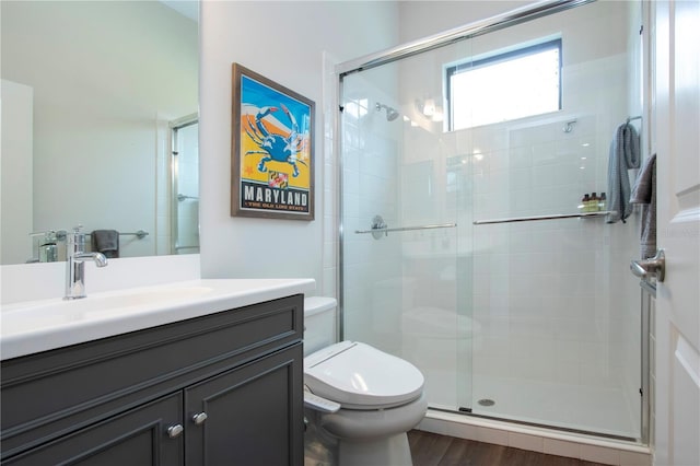 bathroom with vanity, hardwood / wood-style floors, a shower with door, and toilet