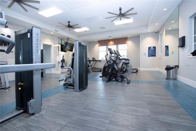 exercise room with ceiling fan and a tray ceiling