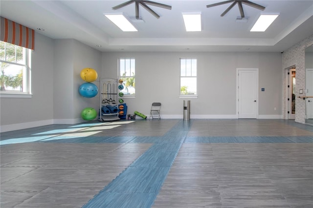 exercise room featuring ceiling fan and a tray ceiling