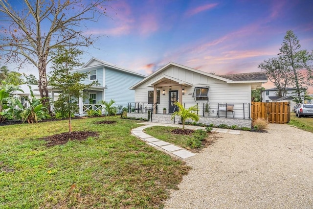 view of front of house featuring a front lawn, fence, a porch, and board and batten siding