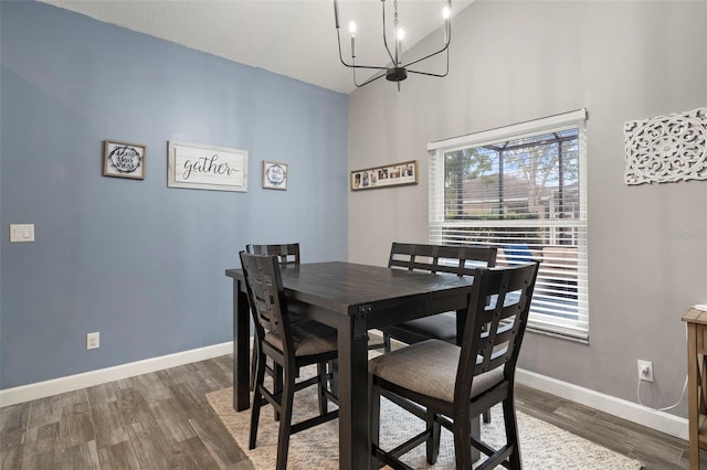 dining space with an inviting chandelier, vaulted ceiling, and dark hardwood / wood-style floors