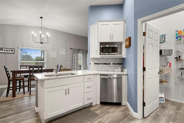 kitchen with tasteful backsplash, white cabinetry, sink, kitchen peninsula, and stainless steel appliances