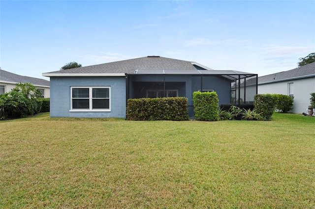 rear view of house with a yard and glass enclosure