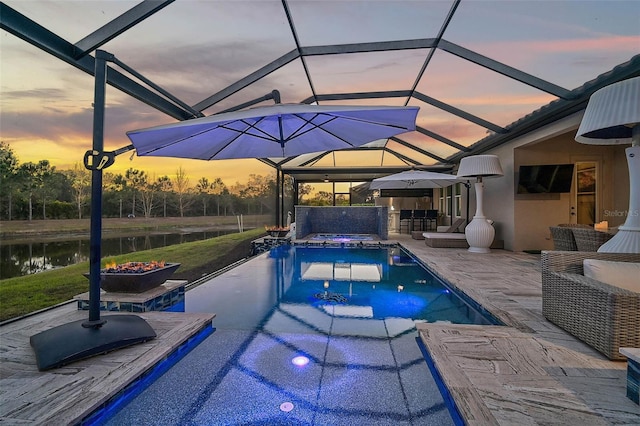 pool at dusk featuring an outdoor pool, glass enclosure, outdoor dry bar, and a patio