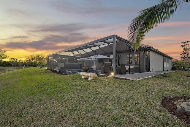 back of house featuring a yard, a lanai, a patio, and stucco siding