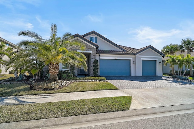 view of front facade with a garage, decorative driveway, a tiled roof, and stucco siding