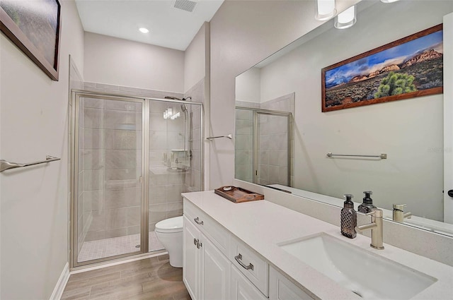 full bathroom with toilet, wood finished floors, visible vents, vanity, and a stall shower