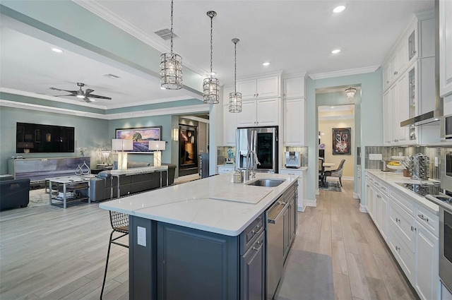 kitchen featuring appliances with stainless steel finishes, white cabinets, a sink, and ornamental molding