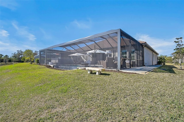 rear view of house with glass enclosure, a patio area, an outdoor pool, and a yard