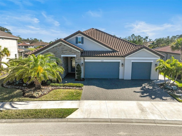 view of front of home with a tiled roof, decorative driveway, an attached garage, and stucco siding