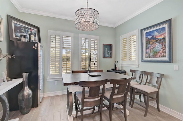 dining room with light wood-type flooring, baseboards, a notable chandelier, and ornamental molding