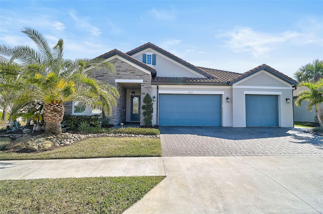 ranch-style house featuring a garage, a tiled roof, stone siding, decorative driveway, and stucco siding