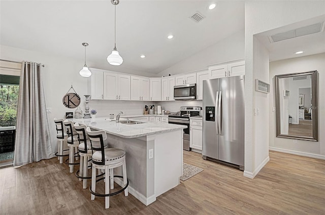 kitchen featuring a breakfast bar, white cabinetry, hanging light fixtures, stainless steel appliances, and light stone counters