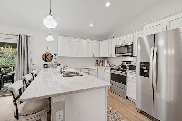 kitchen featuring appliances with stainless steel finishes, sink, a breakfast bar area, hanging light fixtures, and kitchen peninsula